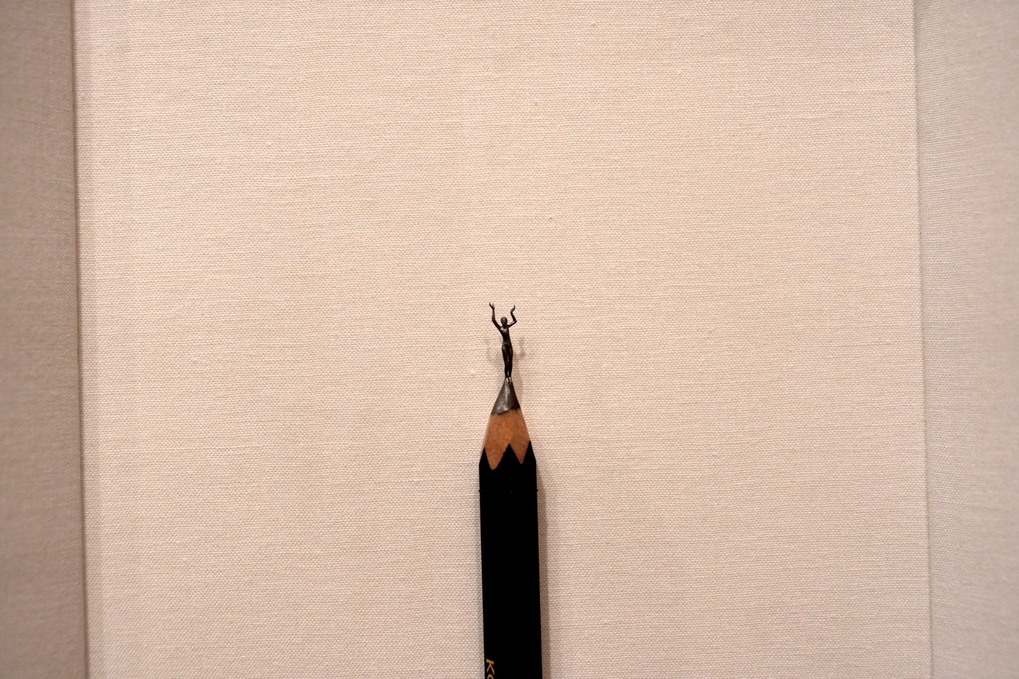 Picture of a sculpture of a dancer carved. The sculpture is carved out of the leaded point of a standard pencil.